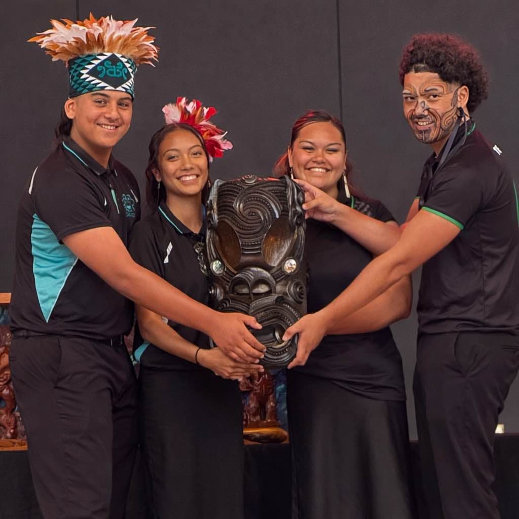 Four members of the Ngaru Pou whānau holding a carved taonga together